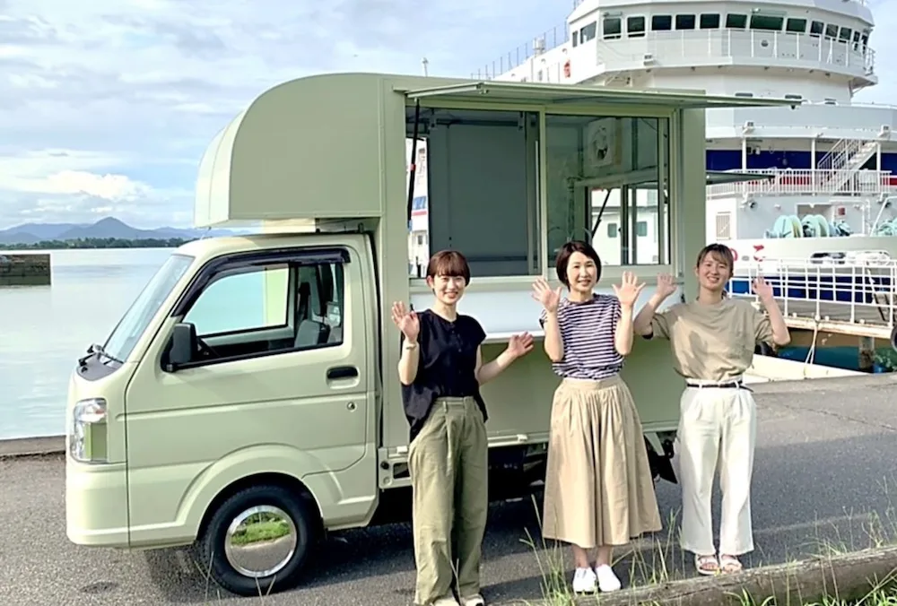 グリーンのキッチンカーと女性3人